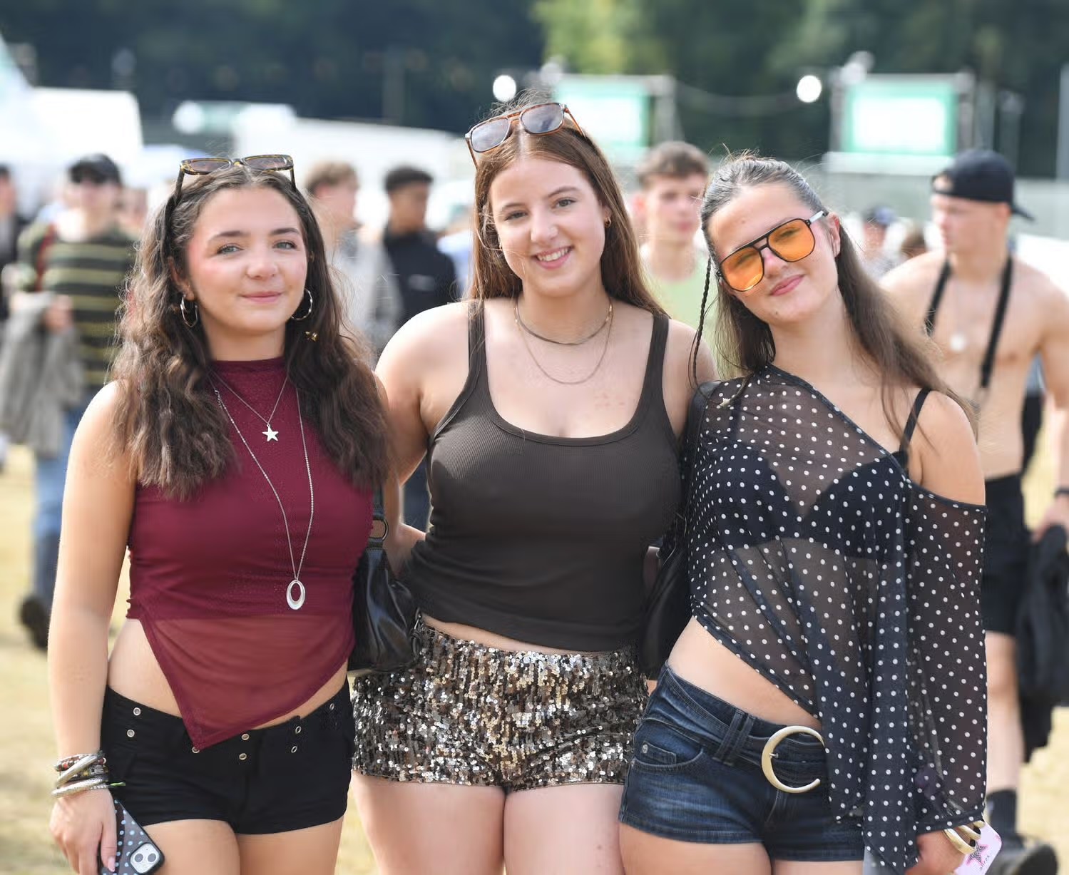 Three friends posing together in the sunshine at Leeds Festival