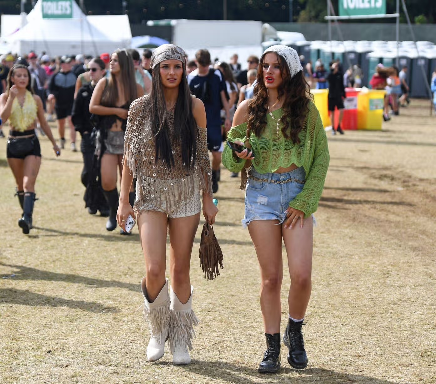 Two festival-goers walking through the arena in festival outfits