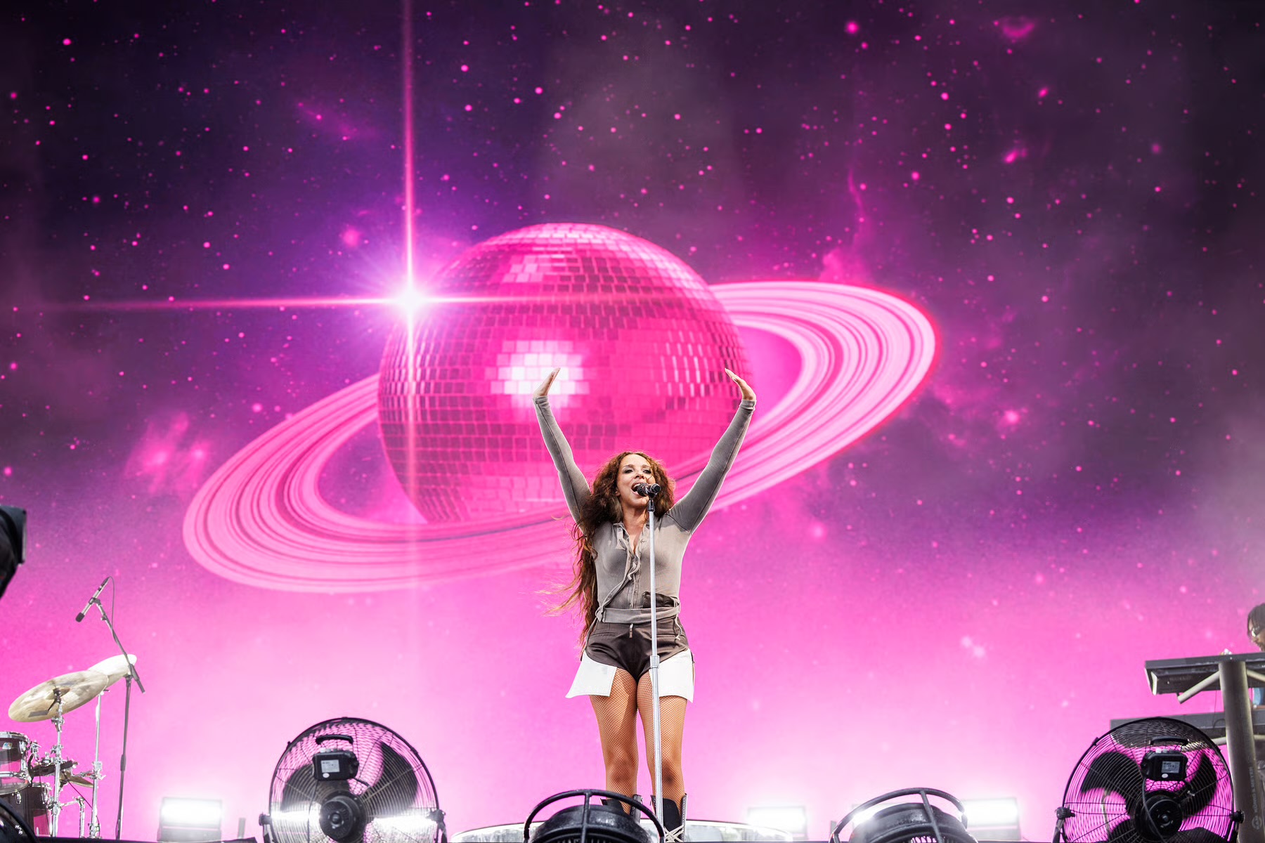 Singer performing in front of a giant pink disco ball screen at Reading