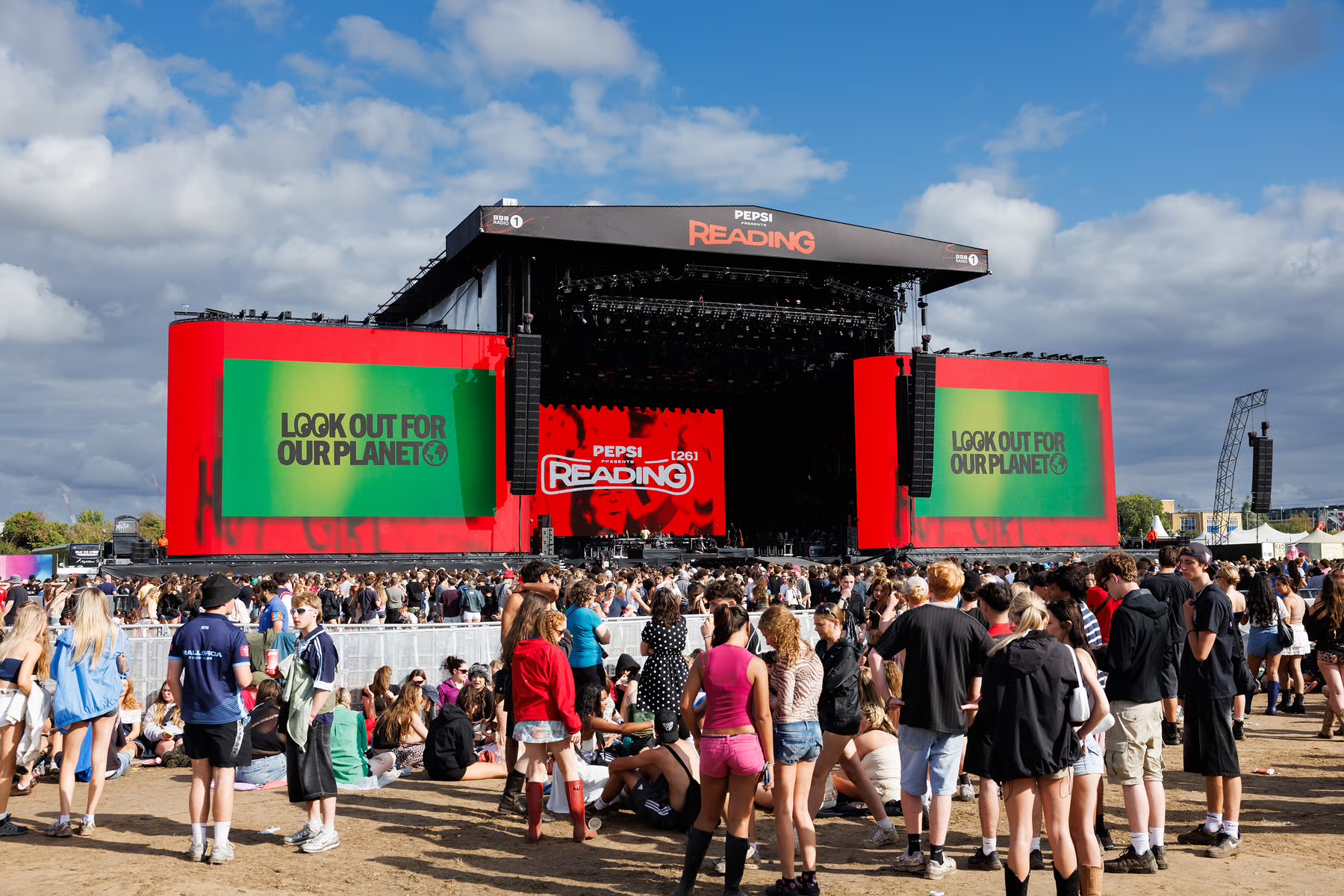Reading Festival main stage with red screens and a large daytime crowd